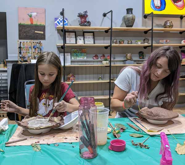 mother and daughter painting a leaf bowl